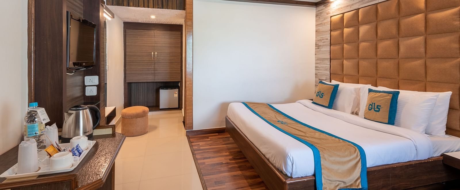 A welcoming hotel room with a comfortable bed, a TV, a mini-fridge, and a balcony offering a view - DLS Meghavan Resort